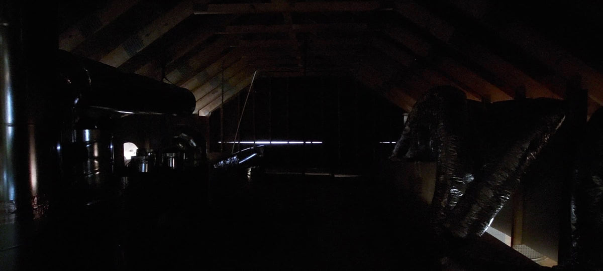 Very dark attic space with insulation and ductwork